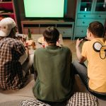 Three young men enjoying a home gaming session together, playing video games in a cozy indoors setting. — examplearticle