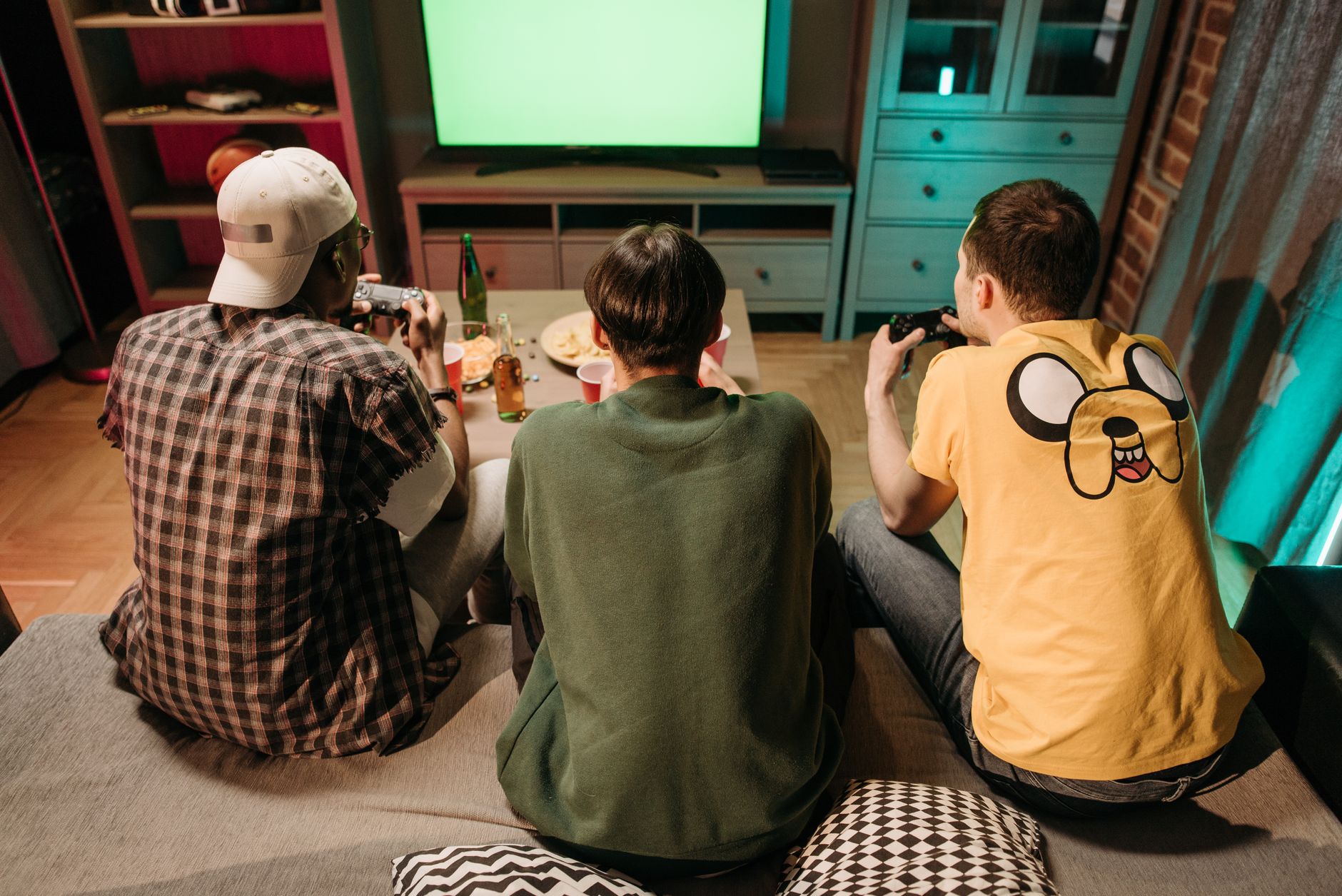 Three young men enjoying a home gaming session together, playing video games in a cozy indoors setting. — examplearticle