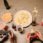 Two gamers playing video games with snacks and drinks on table, a perfect setup for gaming night. — Why Gamers are Flocking t